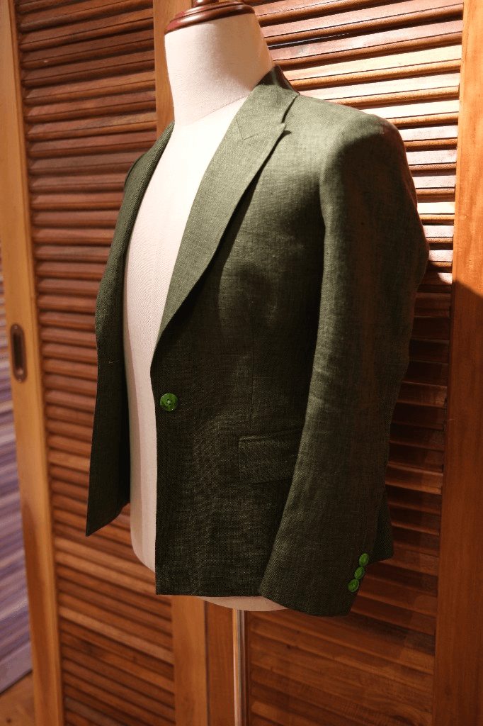 Dark green linen blazer with bright green buttons on mannequin