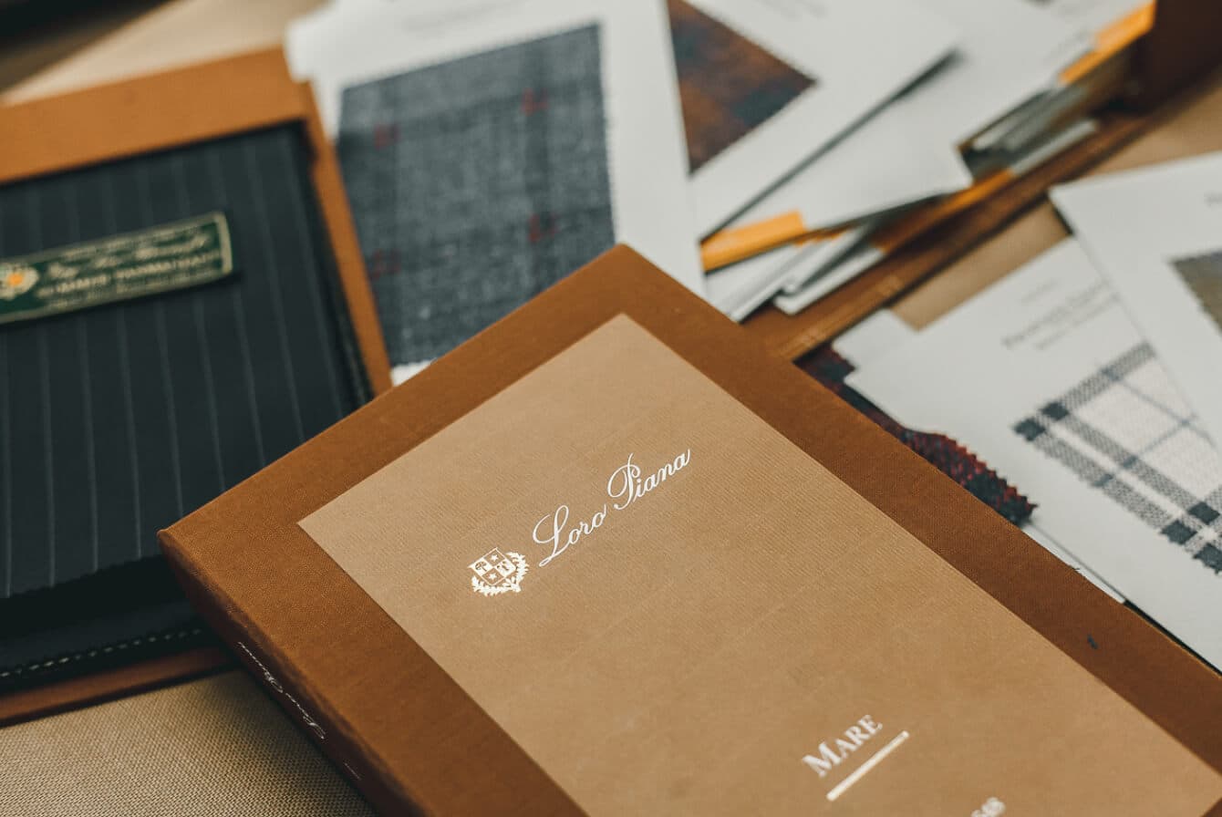 Loro Piana fabric swatch book with surrounding fabric samples on table