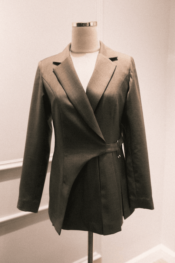 Taupe wrap-style blazer with gold buckle on mannequin