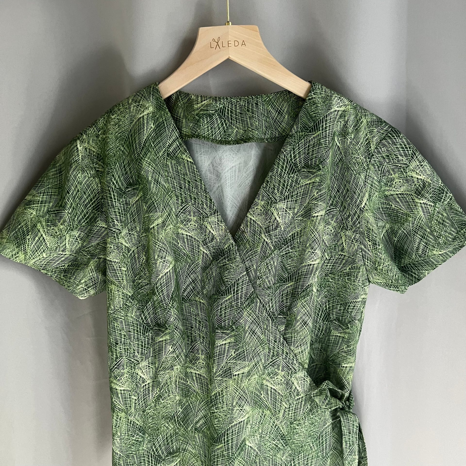 Green leaf print short-sleeve wrap dress on a LALEDA hanger