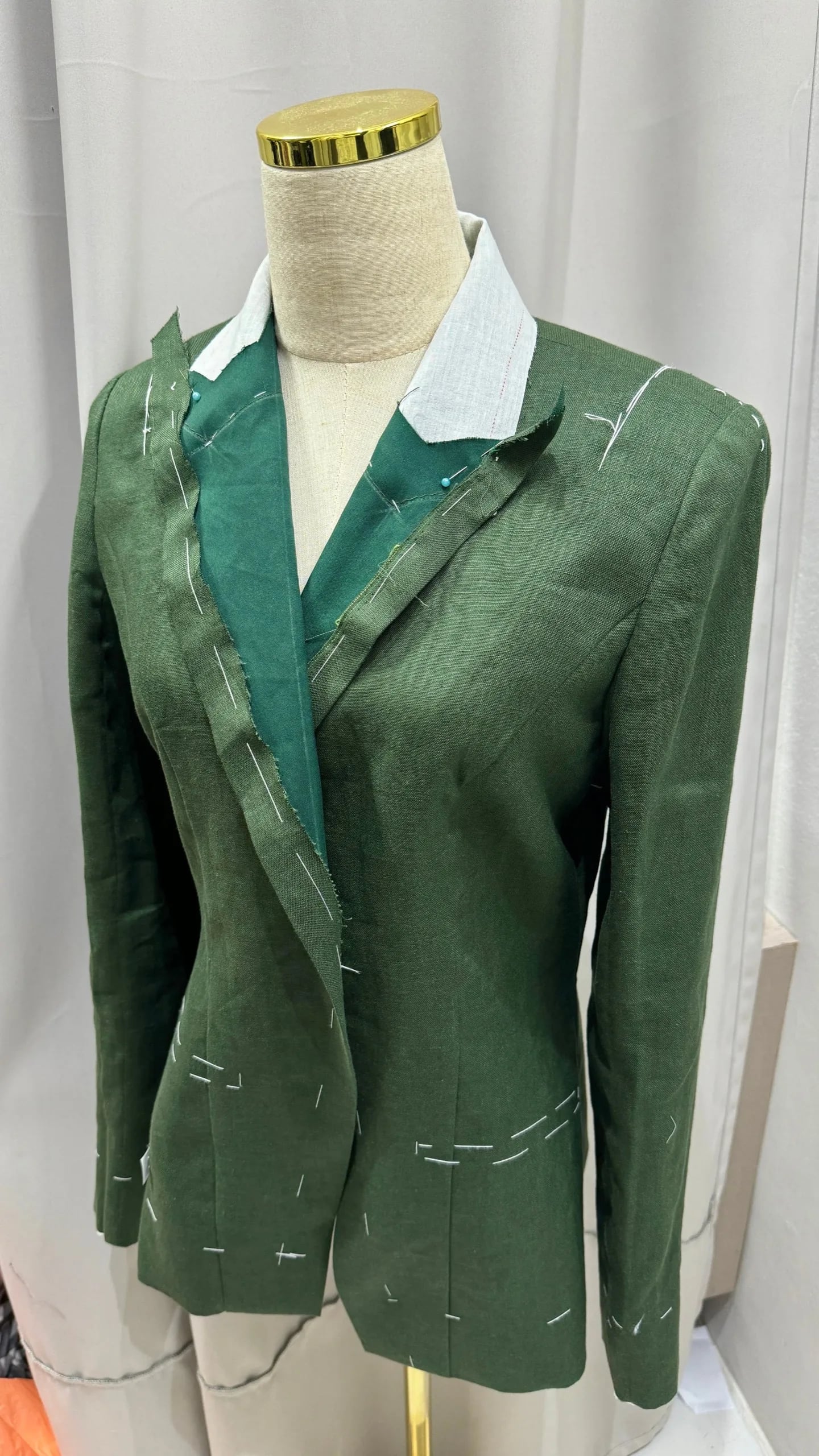 A green linen blazer in basting during fitting at LALEDA
