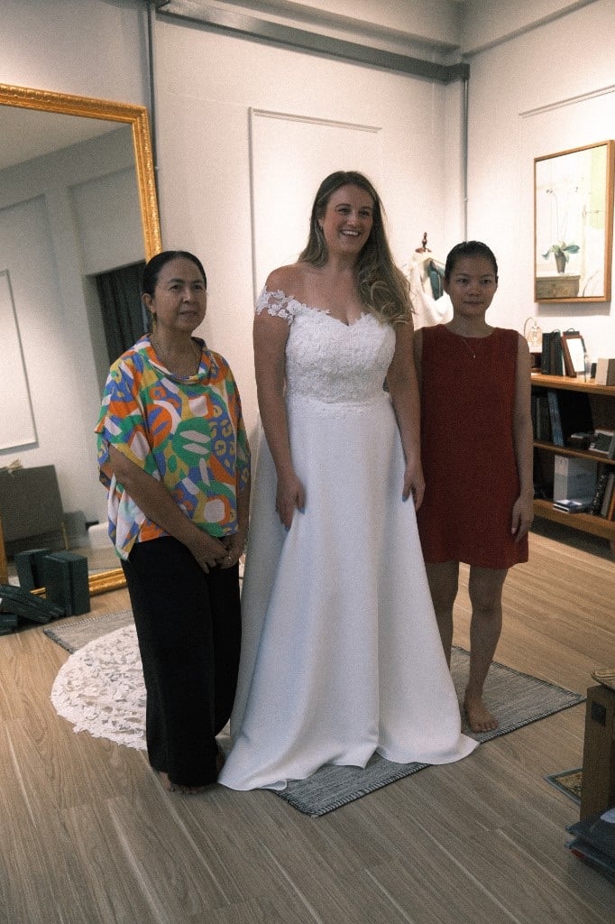Bride in an off-the-shoulder white lace wedding gown during fitting at LALEDA Tailor