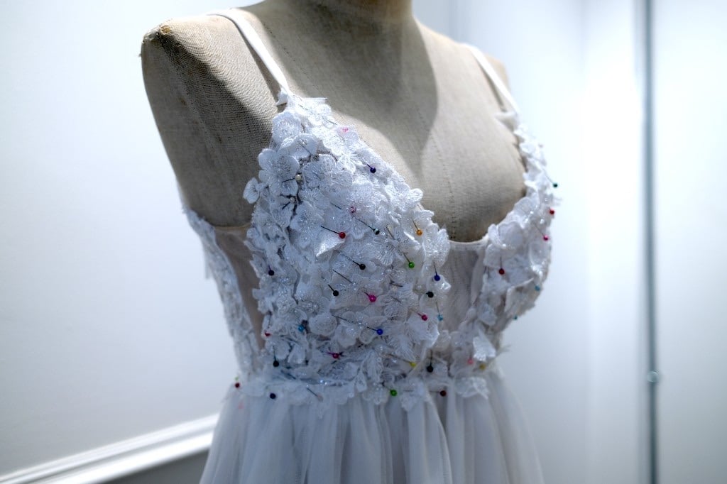 White wedding dress lace bodice in progress on a mannequin with tailoring pins