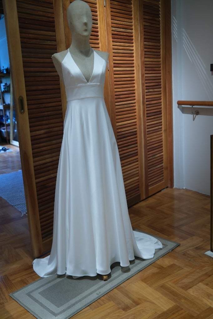 White halter-neck A-line gown with a train on a mannequin