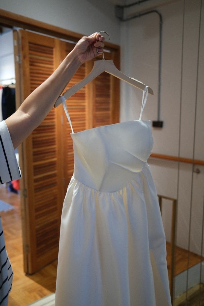 Elegant white strapless wedding gown with gathered skirt on a hanger