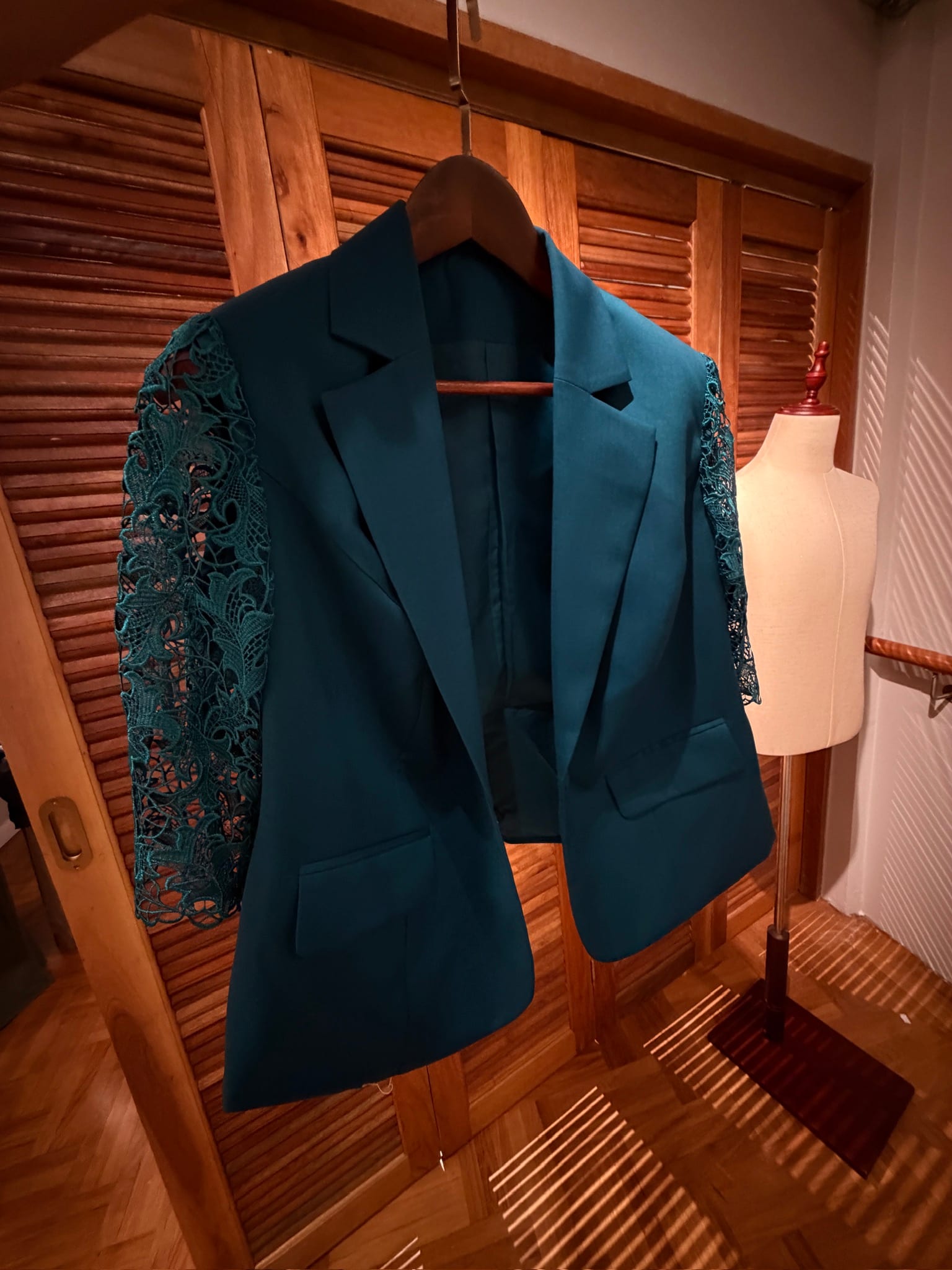 Teal wool blazer with lace sleeves on a hanger at LALEDA Tailor