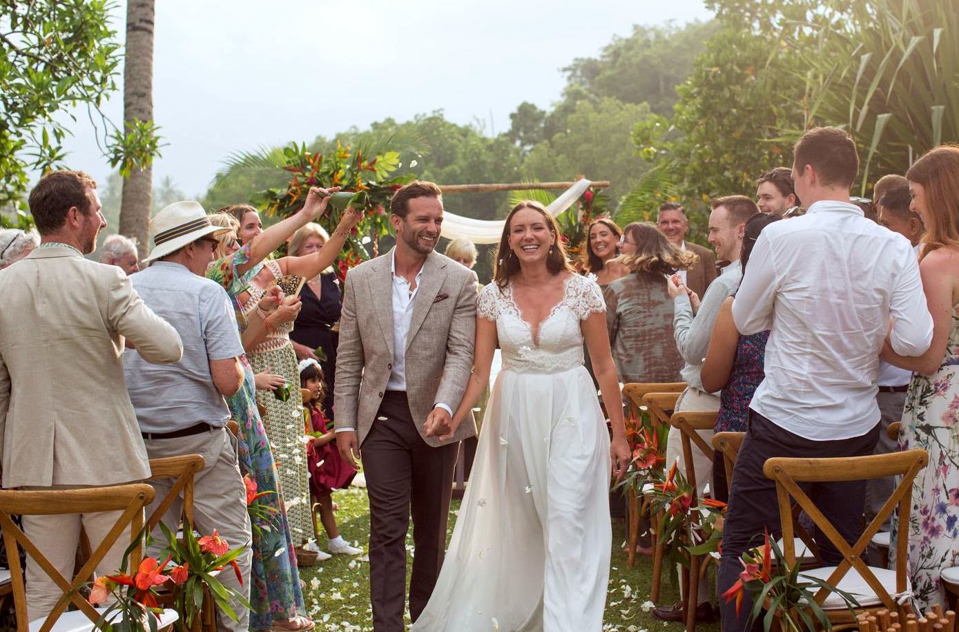 Bride and groom walking the aisle in a lace wedding gown at a tropical garden ceremony