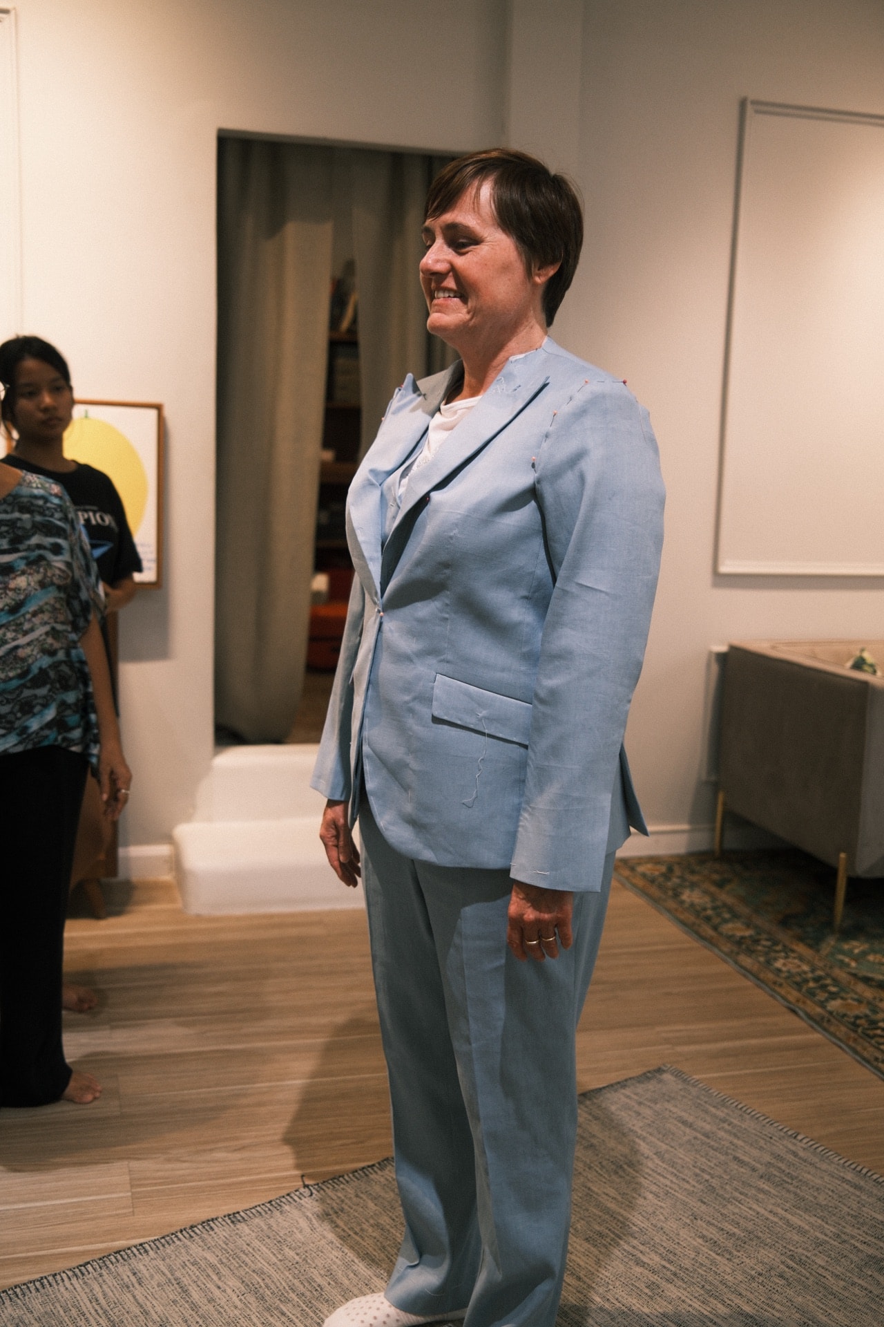 Customer smiling in a baby blue linen suit during fitting at LALEDA Bangkok