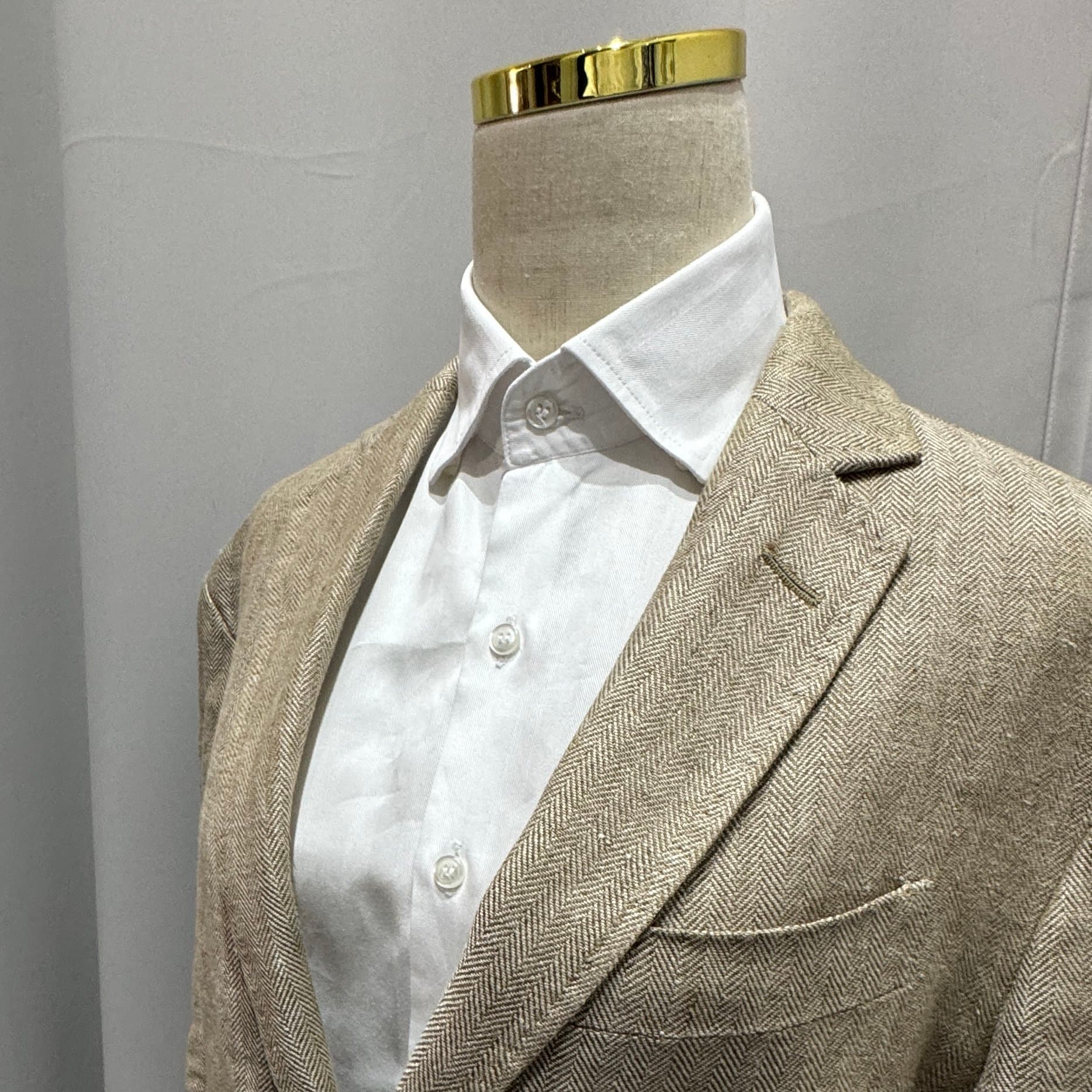 Beige herringbone blazer on a mannequin showing tailored detail