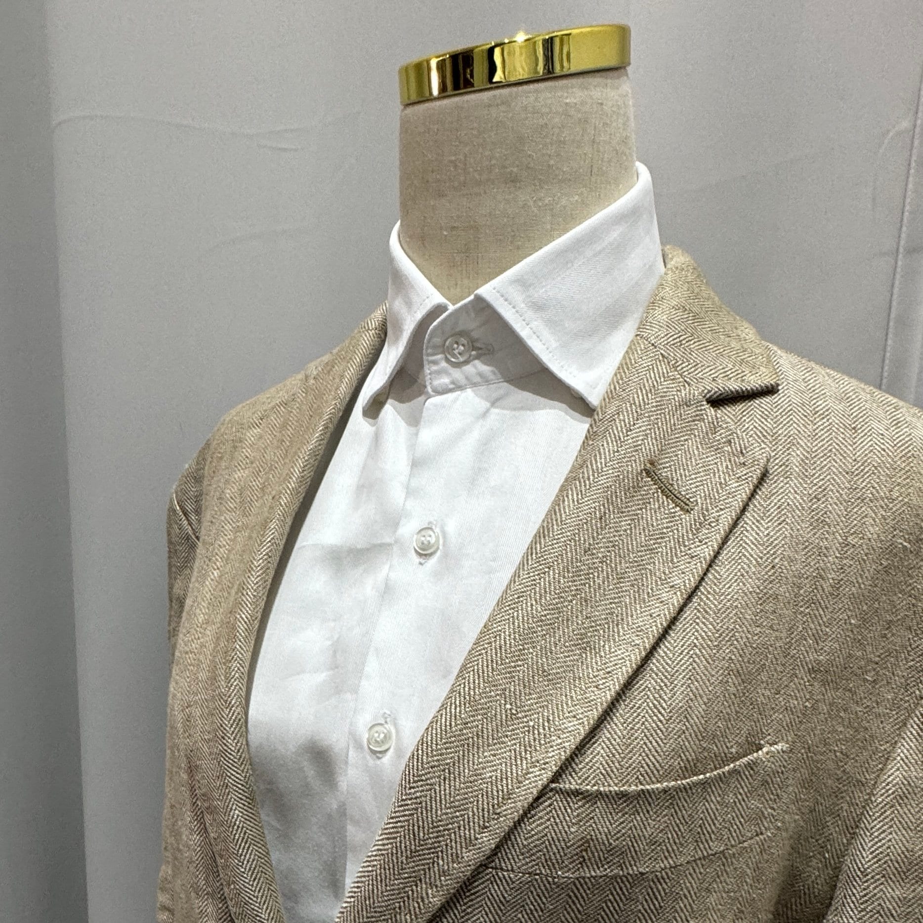 Beige herringbone blazer on a mannequin showing tailored detail