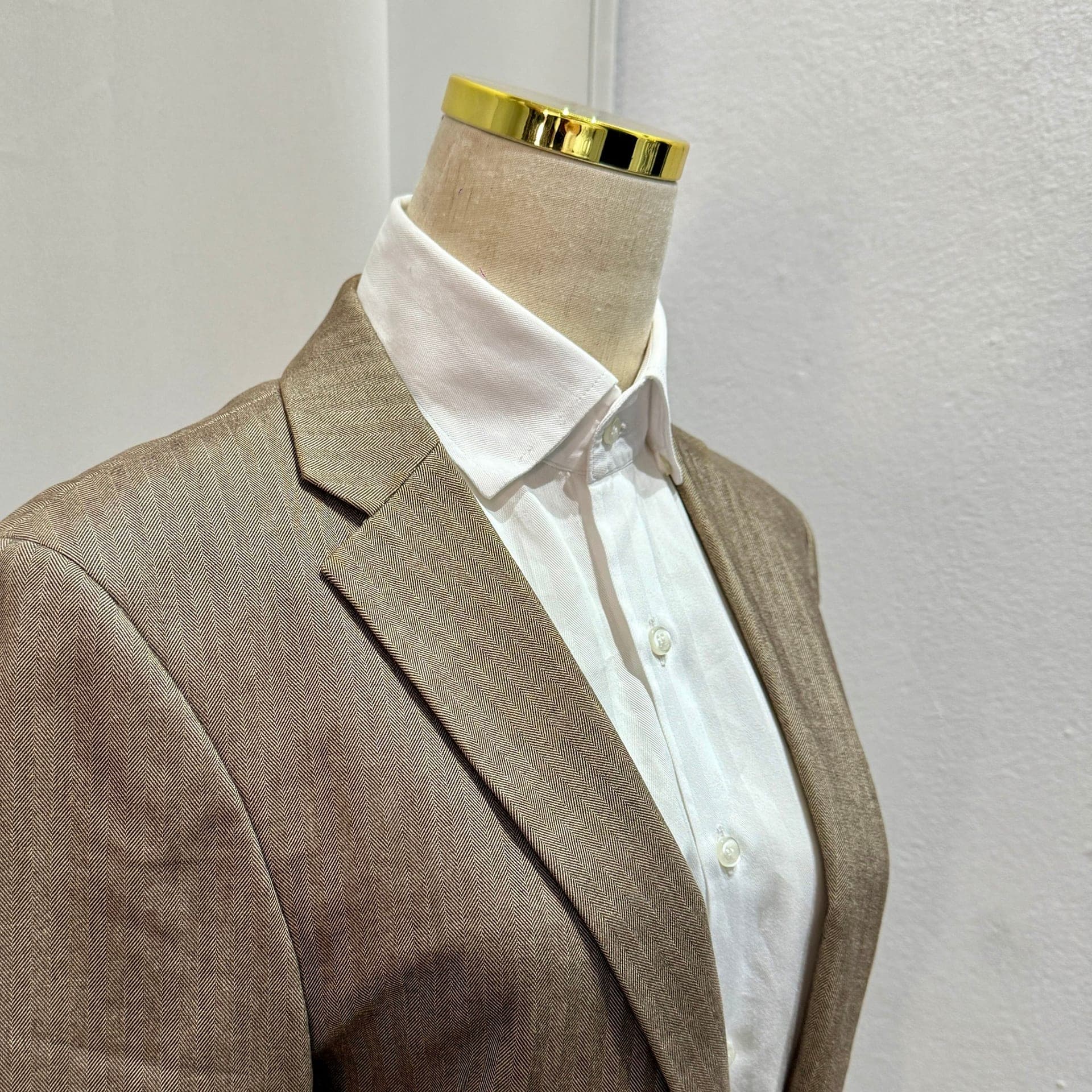 A beige herringbone blazer on a mannequin at the LALEDA atelier