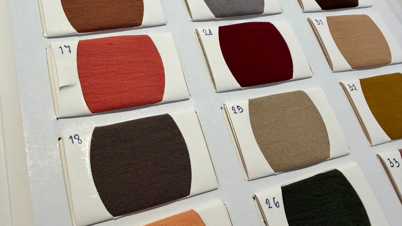 Close-up of Bella fabric swatches in coral, brown, deep red and tan showing the soft matte weave