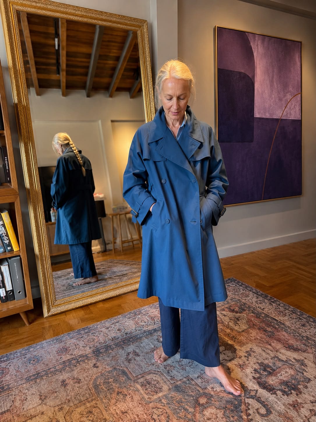 Client wearing a blue gabardine wool double-breasted trench coat at a mirror fitting