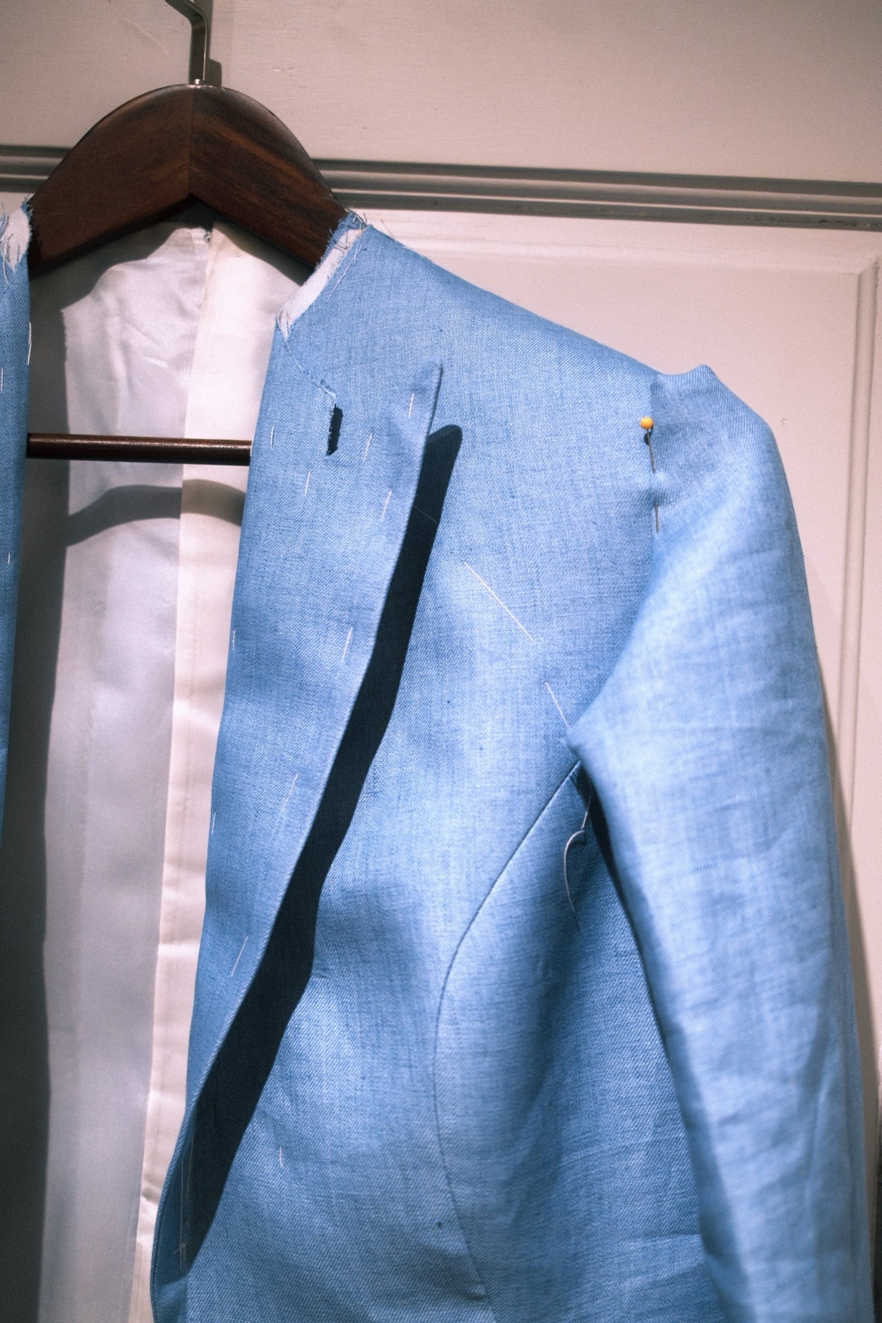 Basting stitches on the shoulder of a blue linen jacket