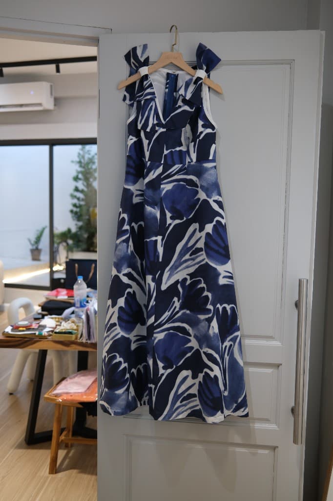 Blue and white abstract floral pattern dress with V-neck and bow straps on hanger