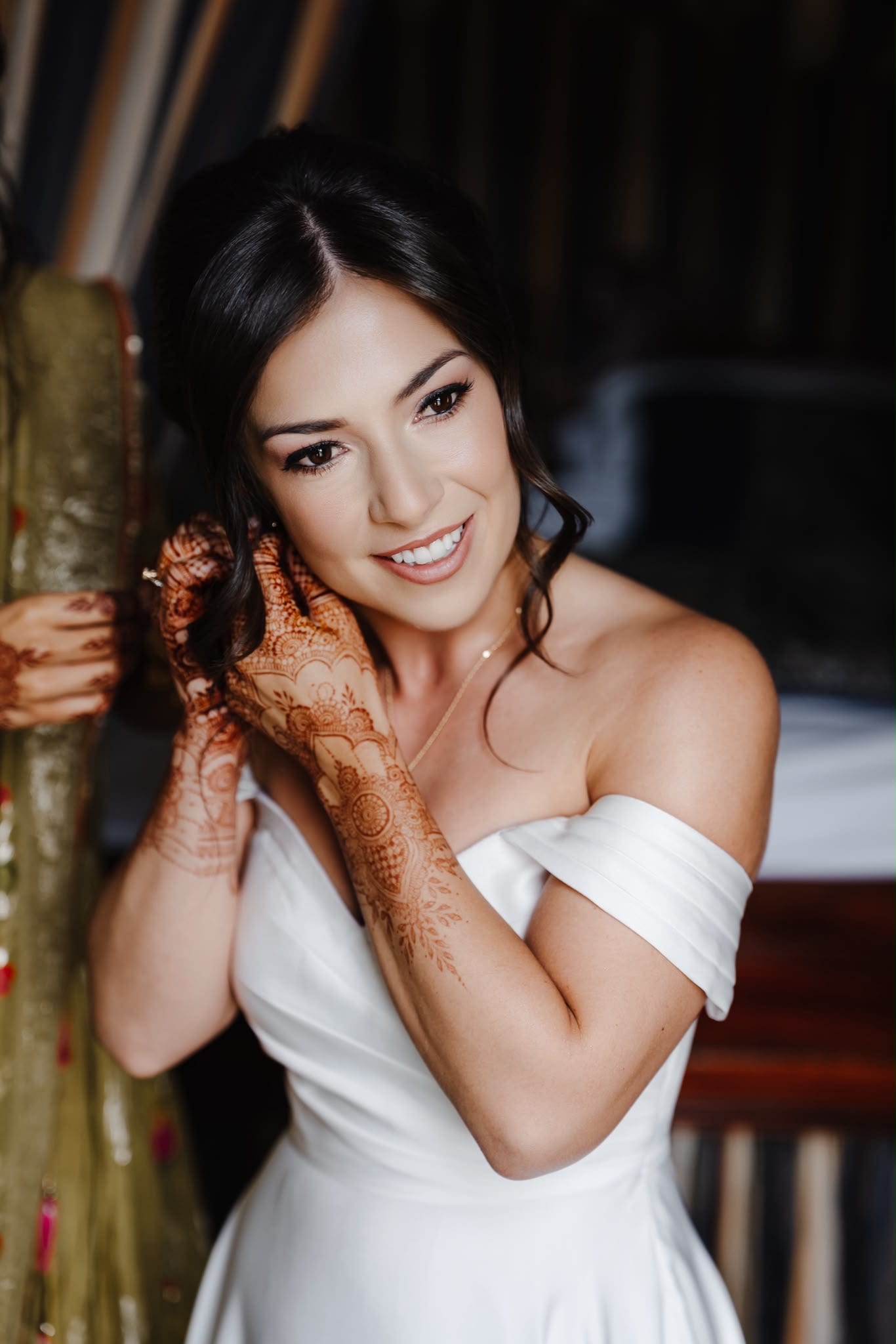 Detail of the bride's henna-covered hands against the off-the-shoulder neckline of her LALEDA wedding dress