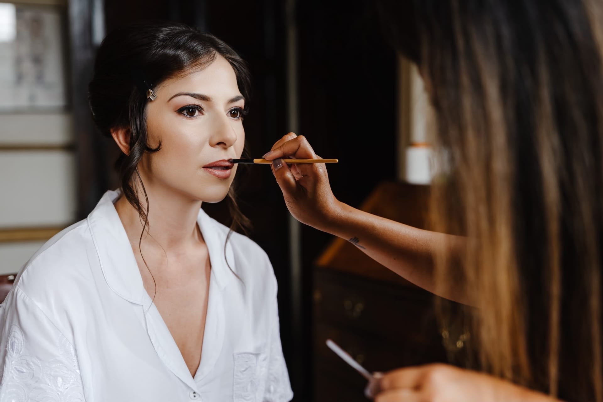 Bride having her makeup finished before an English countryside wedding
