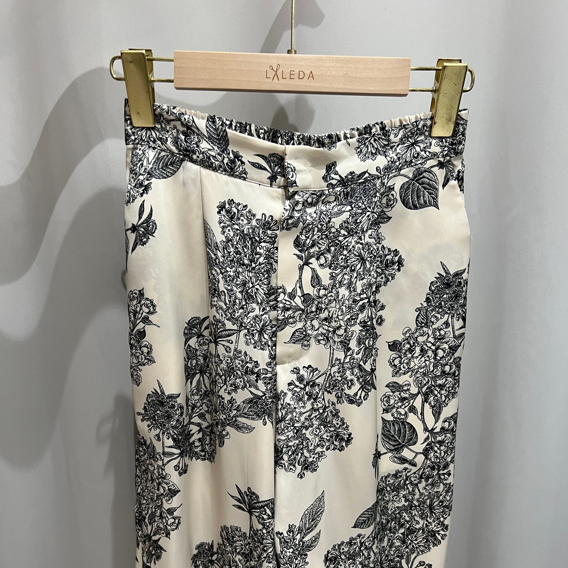 Cream trousers with black floral print on a LALEDA hanger