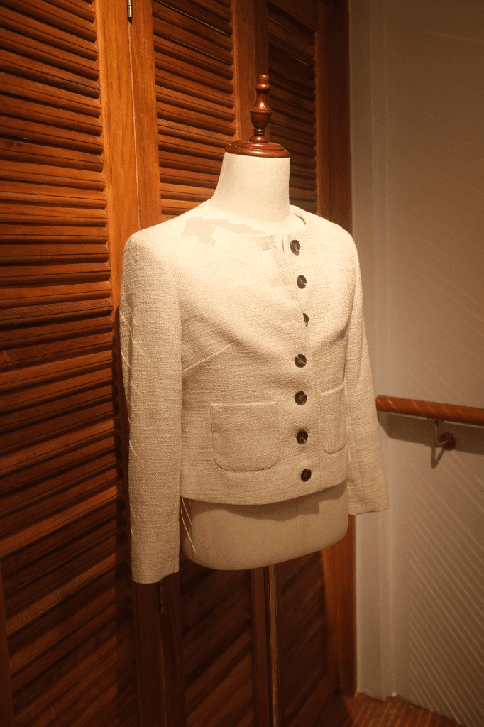 Cream textured collarless women's jacket with patch pockets on mannequin