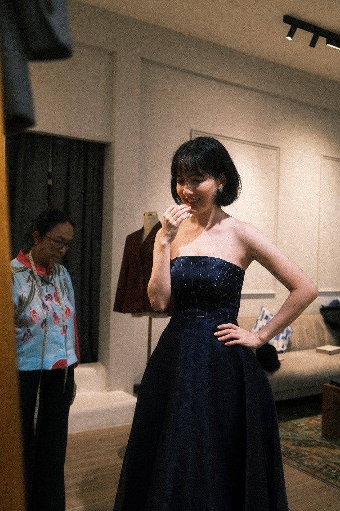 Customer smiling in a dark blue strapless gown during a fitting