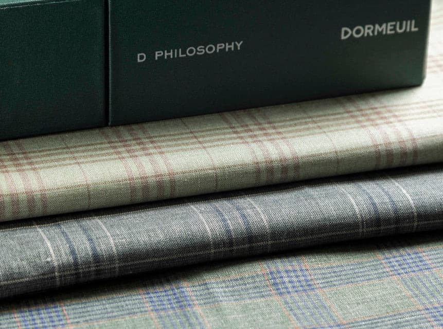 A Dormeuil fabric swatch card open on the atelier table