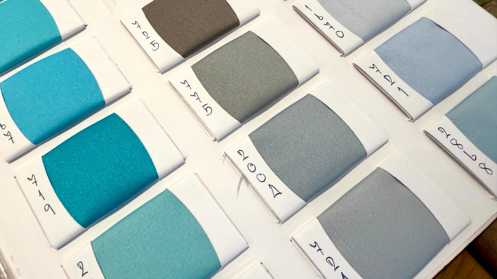 Close-up of duchess satin swatches in teal, grey and soft blue