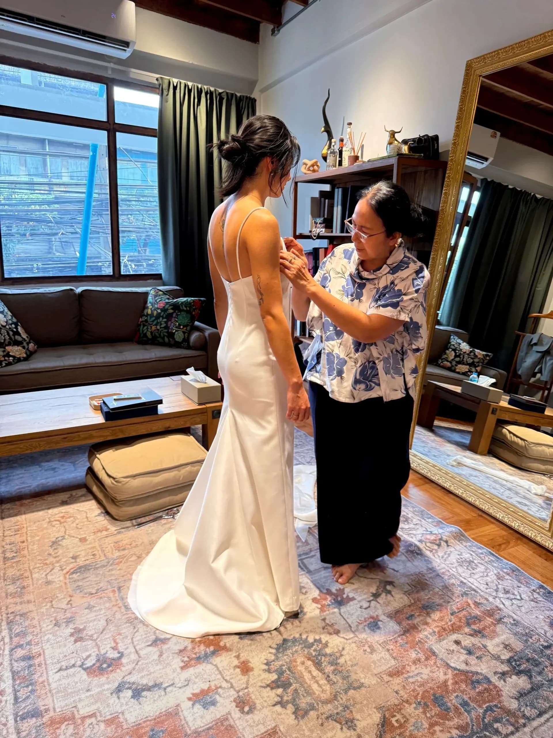 A bride at her fitting while the tailor adjusts the back of her dress