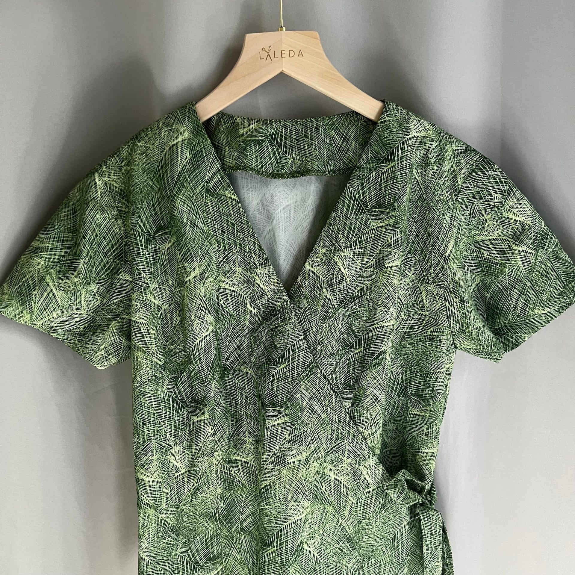 Green leaf print short-sleeve wrap dress on a LALEDA hanger