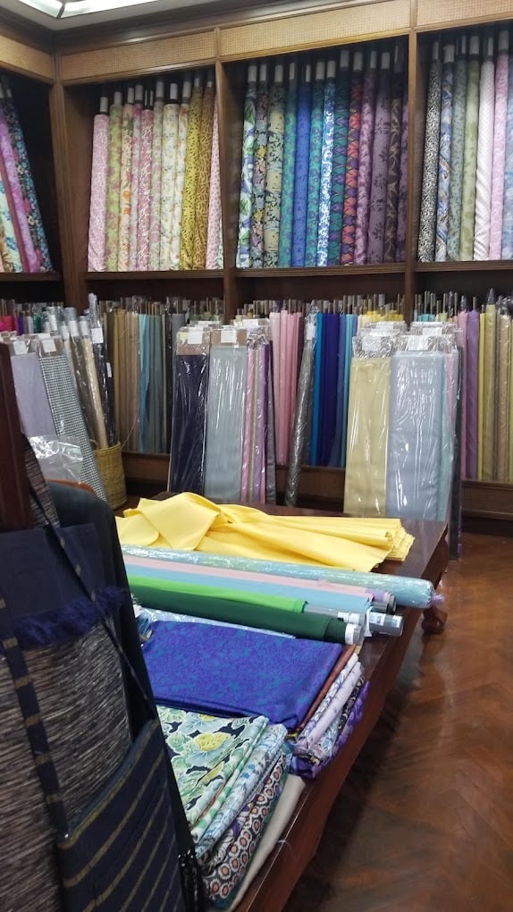 Folded silk fabrics and printed cloth on a table at H.M. Factory for Thai Silk