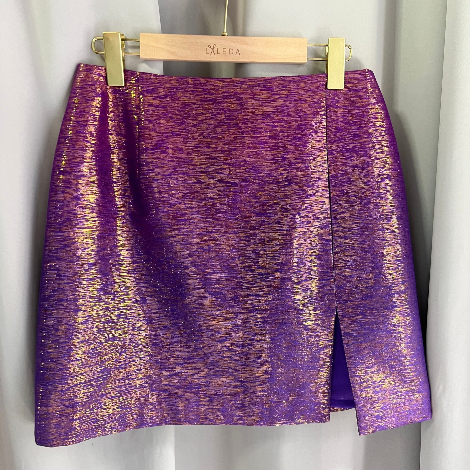 Metallic purple and gold mini skirt with side slit on a LALEDA hanger