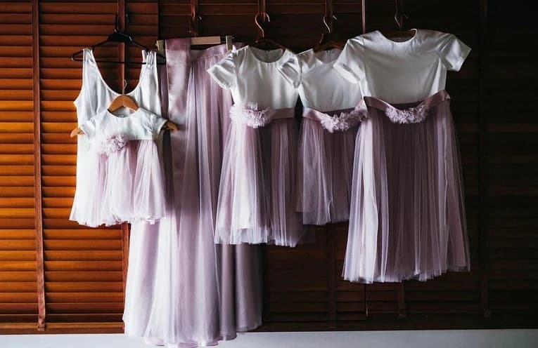 Four daughters in matching purple bridesmaid dresses with tulle skirts