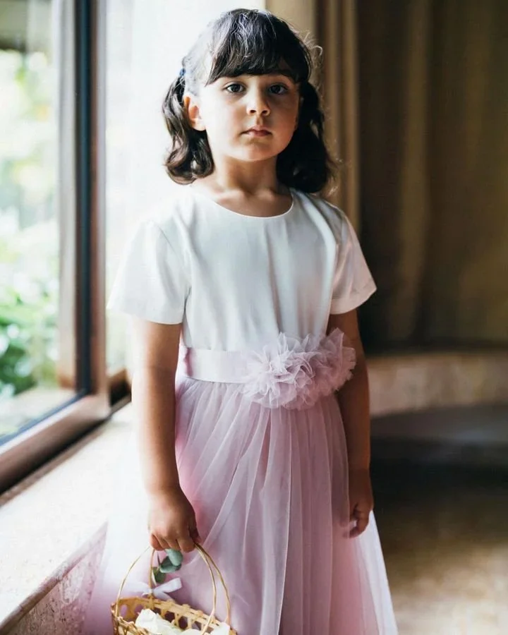 Young flower girl in a soft lilac tulle dress holding a basket