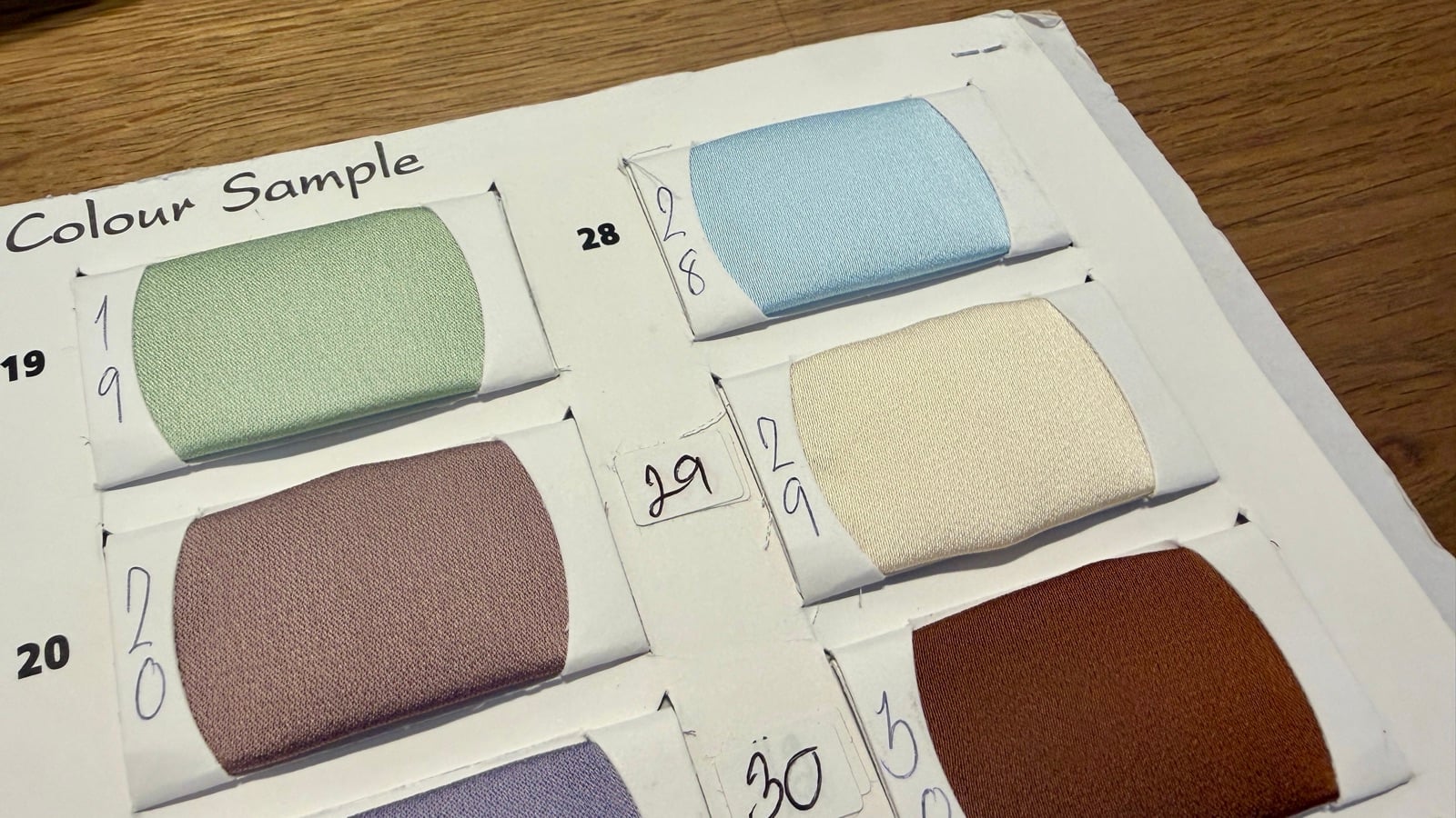 Close-up of Pearl fabric swatches in sage green, soft blue, mauve and cream