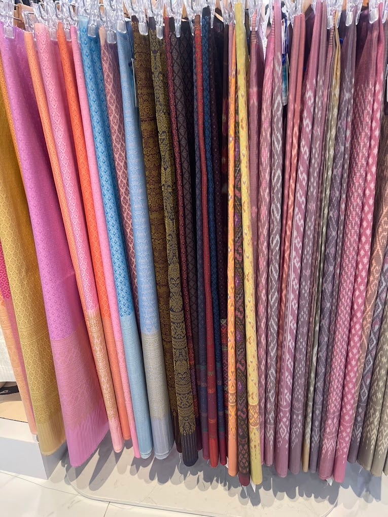 Mudmee and patterned Thai silks on hangers at Sukjai Thaisilk