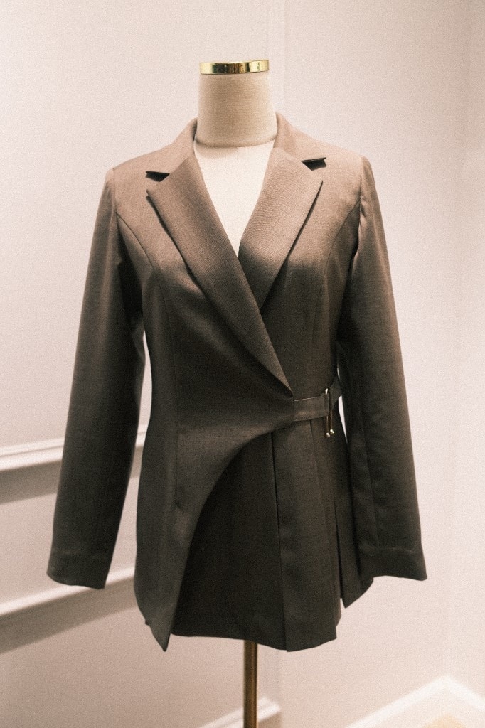 Taupe wrap-style blazer with gold buckle on a mannequin
