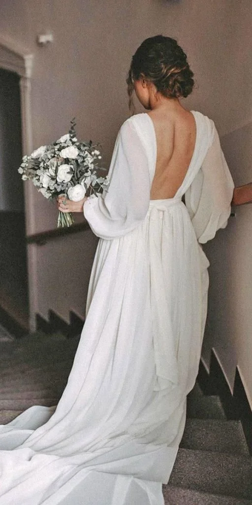 Bride walking down a staircase in a long white wedding dress