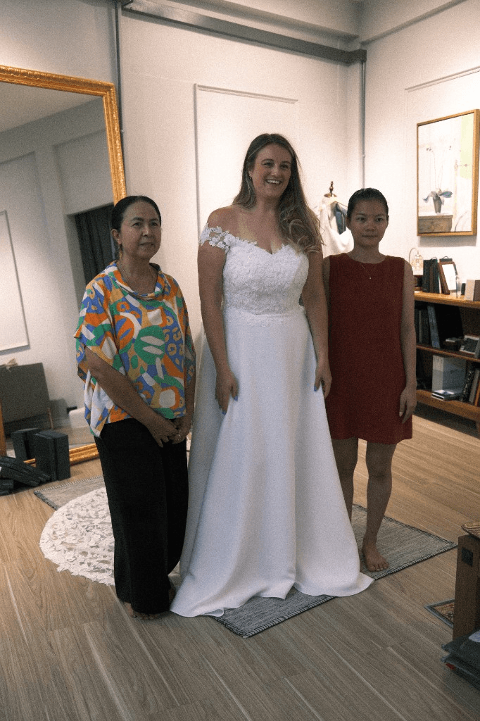 Bride-to-be in off-the-shoulder white lace wedding gown during fitting at LALEDA Tailor
