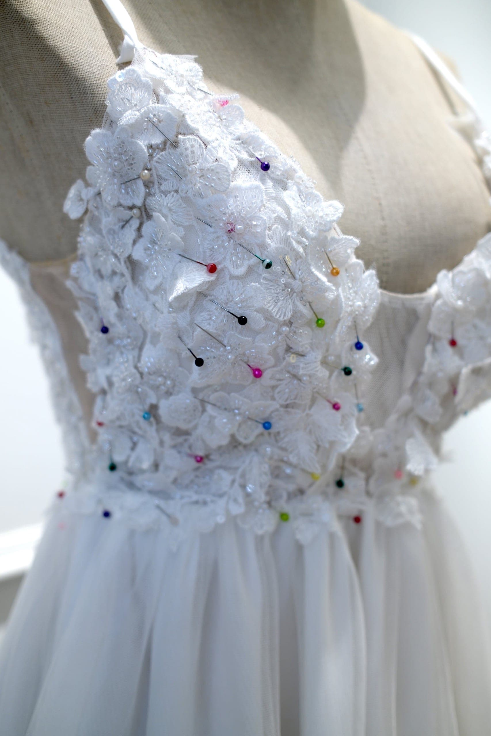 Hands shaping fabric flower details for a wedding dress at the workbench
