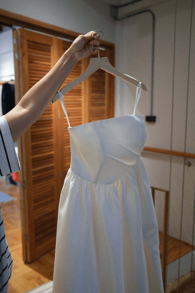 Elegant white strapless wedding gown with gathered skirt on hanger